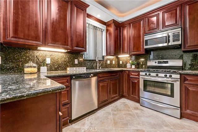 kitchen with stainless steel appliances, dark stone counters, sink, backsplash, and light tile patterned flooring