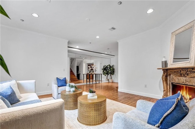 living room featuring a fireplace, crown molding, and light hardwood / wood-style floors