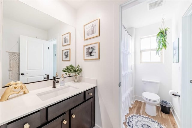 bathroom with toilet, wood-type flooring, and vanity