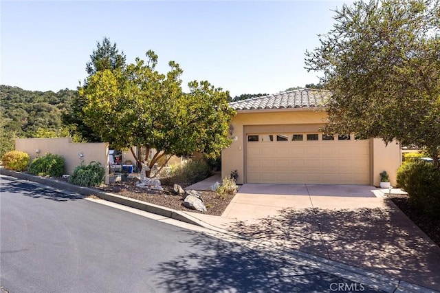 view of front of property featuring concrete driveway, an outdoor structure, a tiled roof, and stucco siding