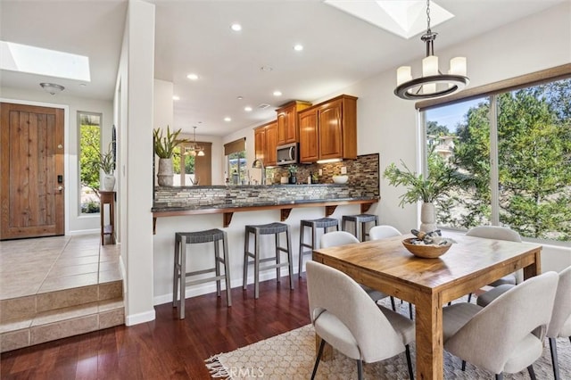 dining room featuring a chandelier, a skylight, wood finished floors, and recessed lighting