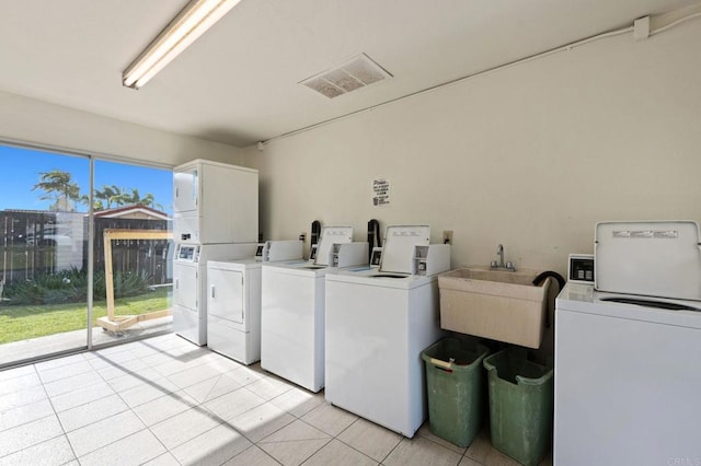 laundry room featuring stacked washing maching and dryer, washer and clothes dryer, sink, and light tile patterned floors