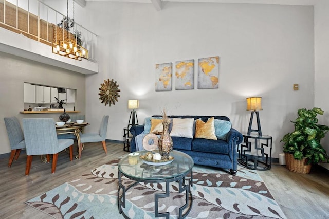 living room with a high ceiling, a notable chandelier, hardwood / wood-style floors, and beamed ceiling