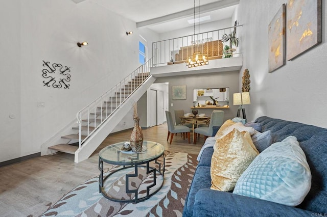 living room featuring beam ceiling, a towering ceiling, an inviting chandelier, and hardwood / wood-style flooring