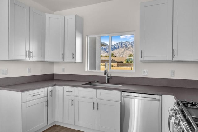 kitchen featuring hardwood / wood-style floors, sink, a mountain view, appliances with stainless steel finishes, and white cabinets