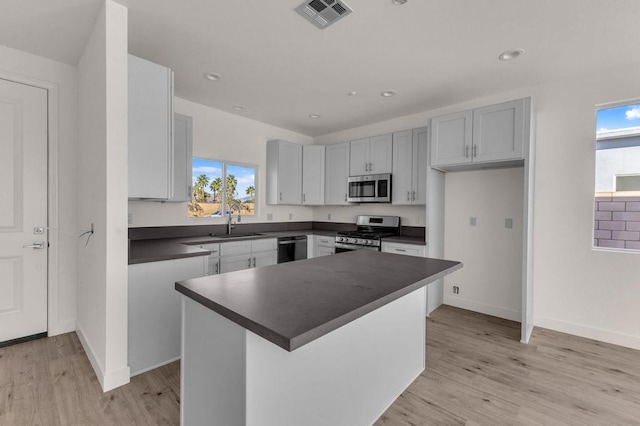 kitchen featuring stainless steel appliances, light hardwood / wood-style floors, a kitchen island, and sink