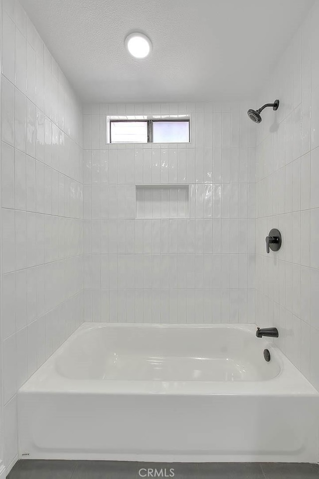 bathroom featuring tiled shower / bath combo and a textured ceiling