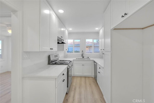 kitchen featuring ceiling fan, sink, stainless steel appliances, light hardwood / wood-style floors, and white cabinets