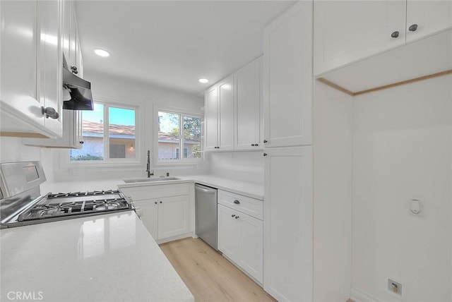 kitchen featuring stainless steel dishwasher, sink, light hardwood / wood-style flooring, white cabinets, and range