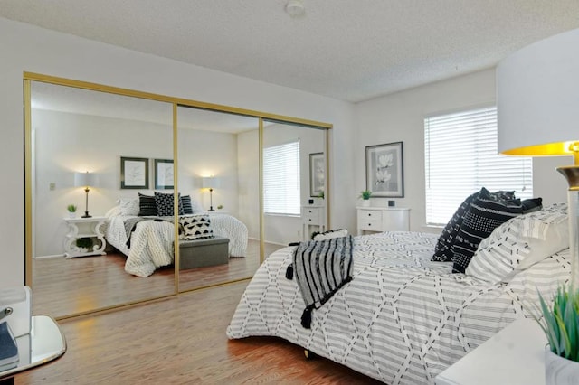 bedroom with a closet, a textured ceiling, and wood-type flooring