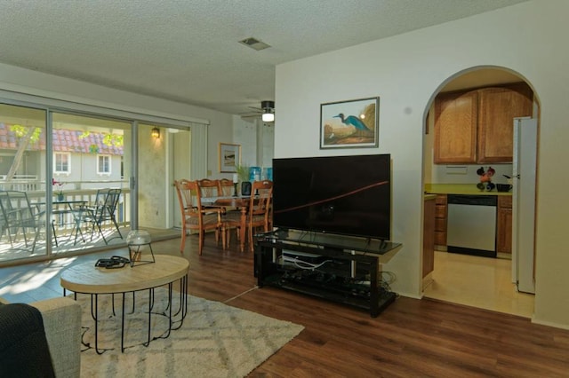 living room with ceiling fan, dark hardwood / wood-style flooring, and a textured ceiling