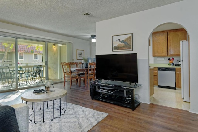 living room with a textured ceiling, ceiling fan, and light hardwood / wood-style floors