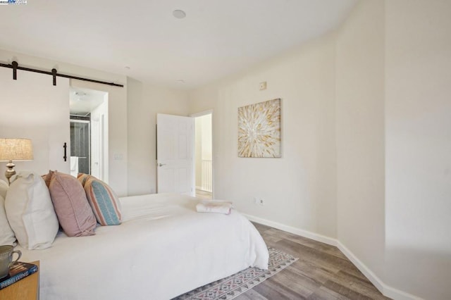 bedroom featuring a barn door and hardwood / wood-style floors