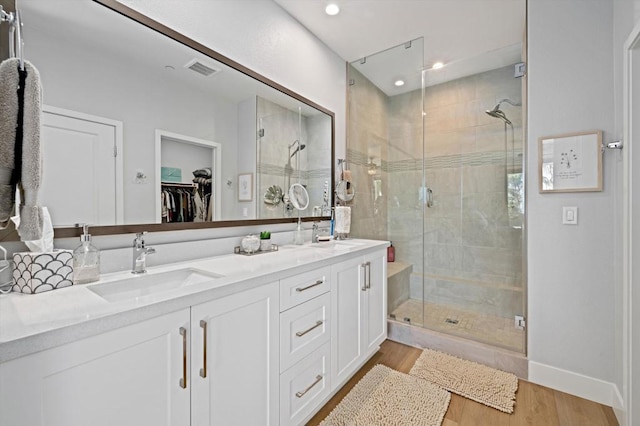 bathroom with hardwood / wood-style flooring, vanity, and a shower with door