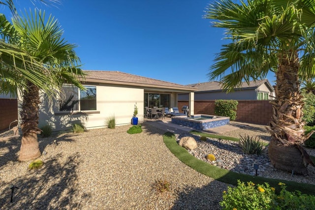 back of house featuring an in ground hot tub and a patio area