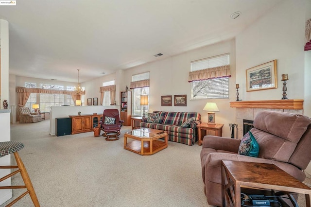 carpeted living room featuring a fireplace, a healthy amount of sunlight, and a notable chandelier