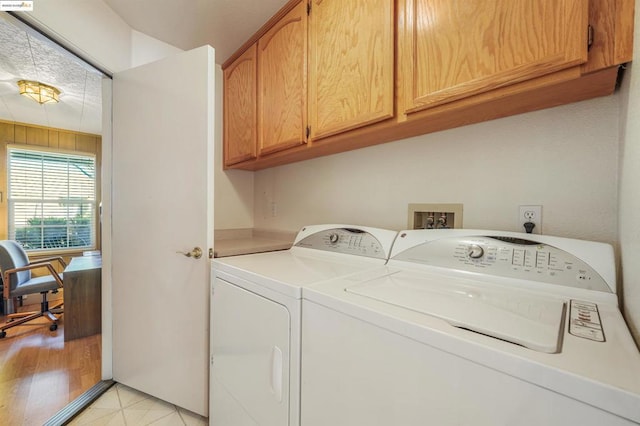 clothes washing area featuring cabinets and washing machine and clothes dryer