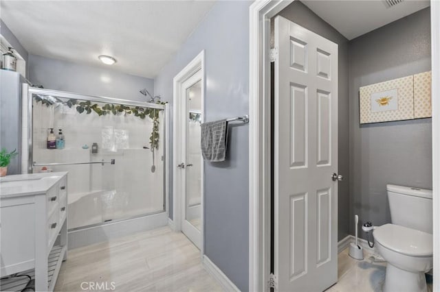 bathroom with toilet, a shower with door, and vanity