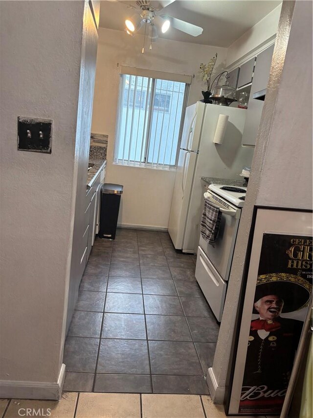 kitchen featuring ceiling fan, white electric stove, and dark tile patterned floors