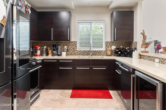 kitchen featuring dark brown cabinets, decorative backsplash, beverage cooler, and sink