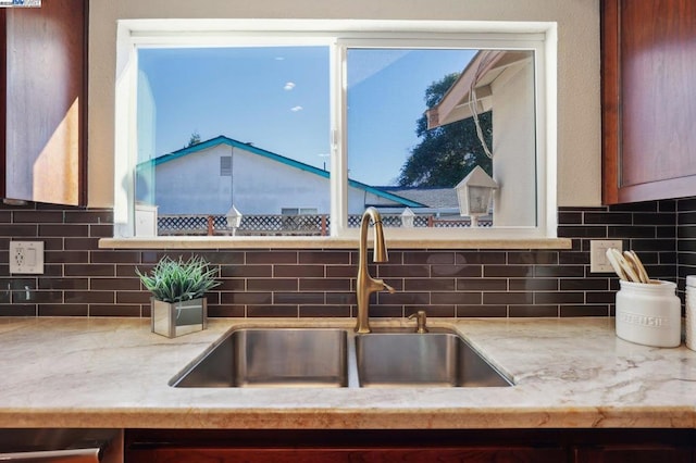 room details featuring sink, stainless steel dishwasher, and backsplash