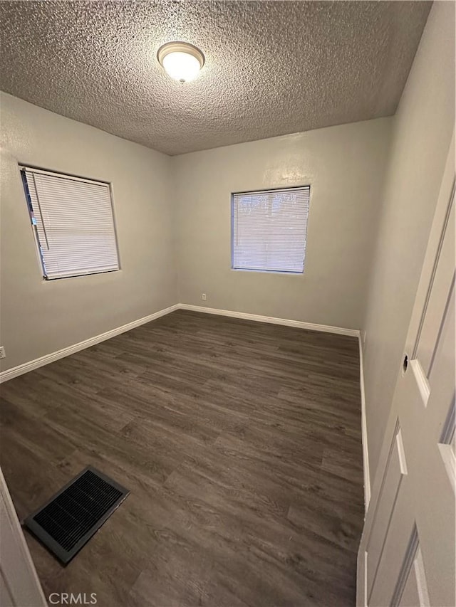 spare room featuring dark hardwood / wood-style floors and a textured ceiling