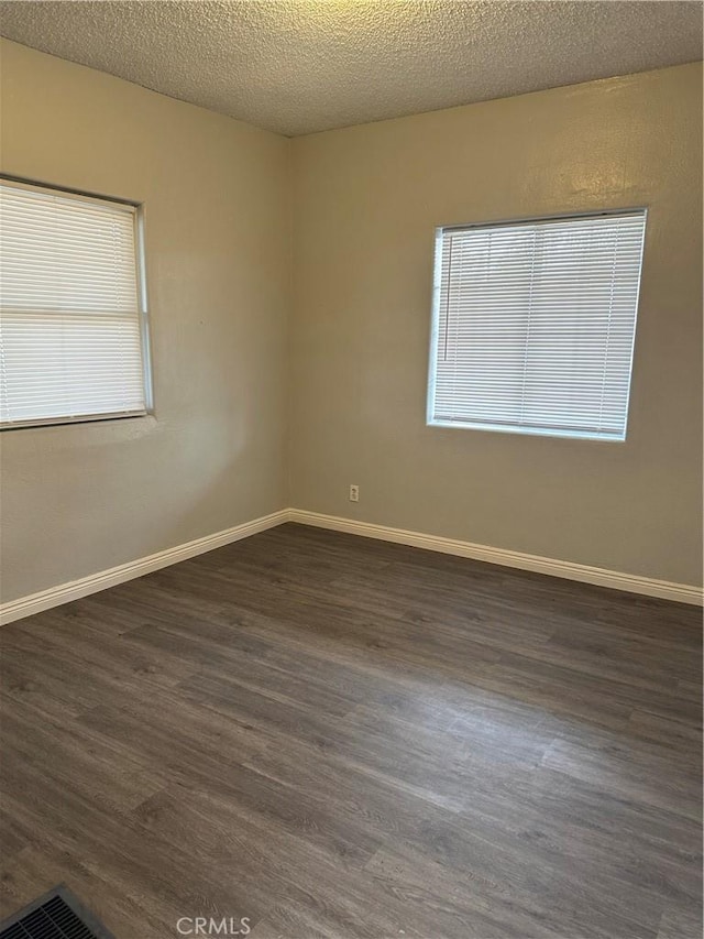 spare room with dark hardwood / wood-style flooring and a textured ceiling