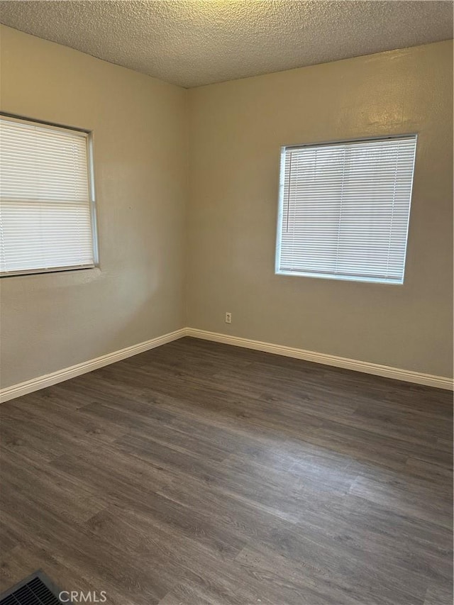 spare room featuring dark wood-type flooring and a textured ceiling