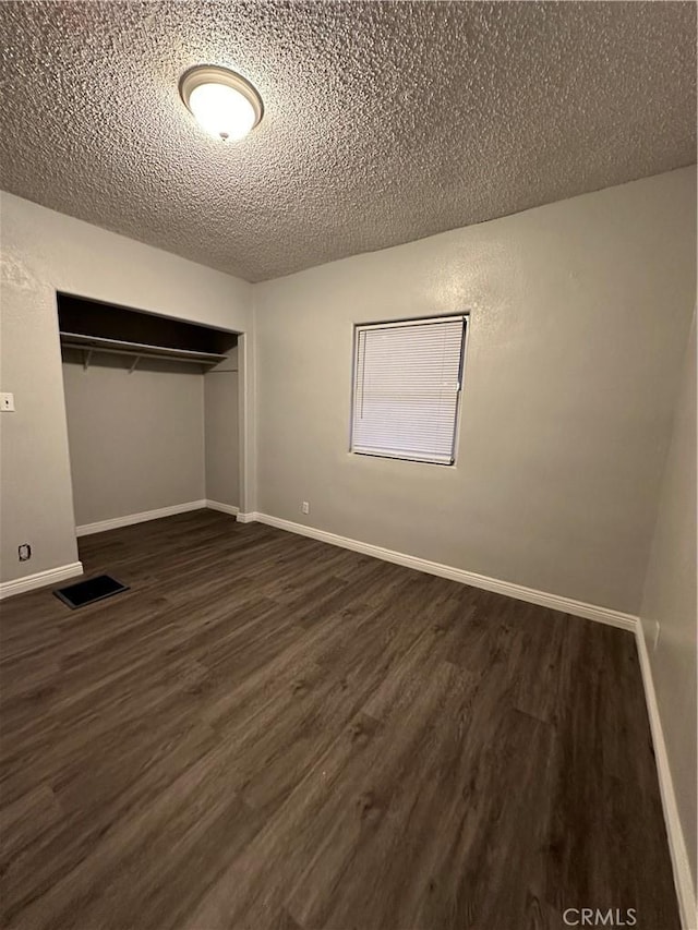 unfurnished bedroom featuring dark hardwood / wood-style flooring, a closet, and a textured ceiling