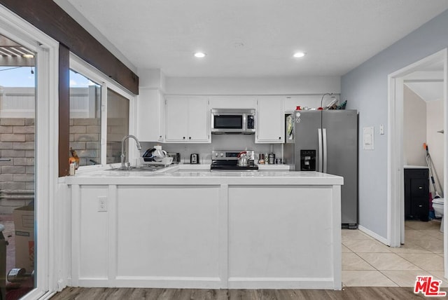 kitchen with sink, white cabinetry, appliances with stainless steel finishes, and kitchen peninsula