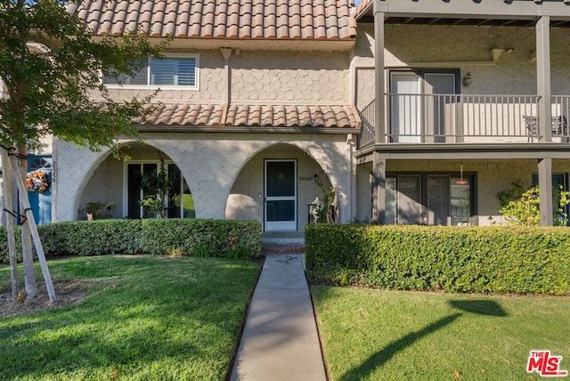 view of front of home with a balcony and a front lawn