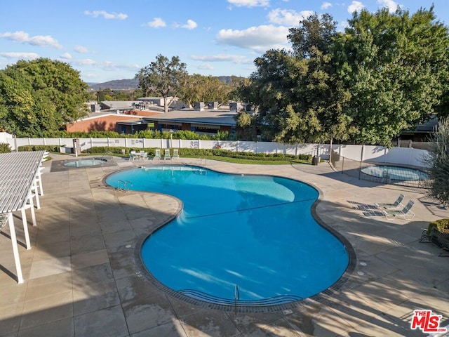 view of pool with a hot tub, a mountain view, and a patio