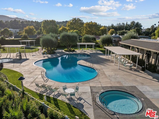 view of swimming pool with a mountain view, a hot tub, and a patio