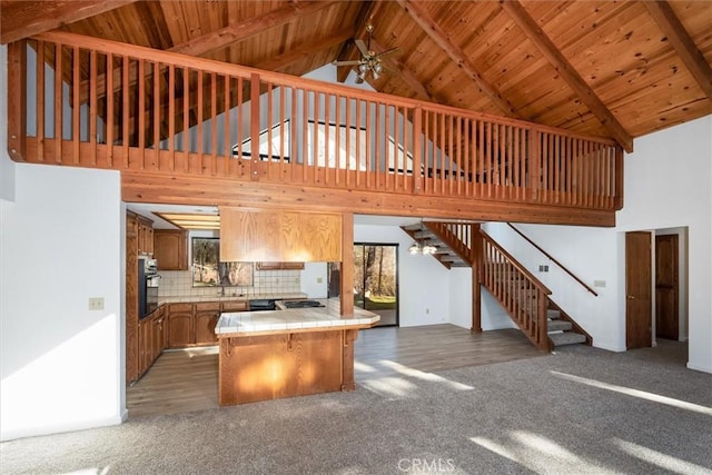 kitchen featuring tasteful backsplash, ceiling fan, tile countertops, high vaulted ceiling, and dark colored carpet