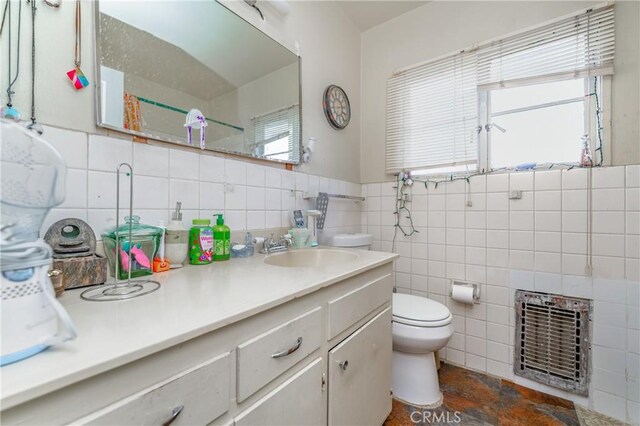 bathroom featuring vanity, toilet, heating unit, and tile walls