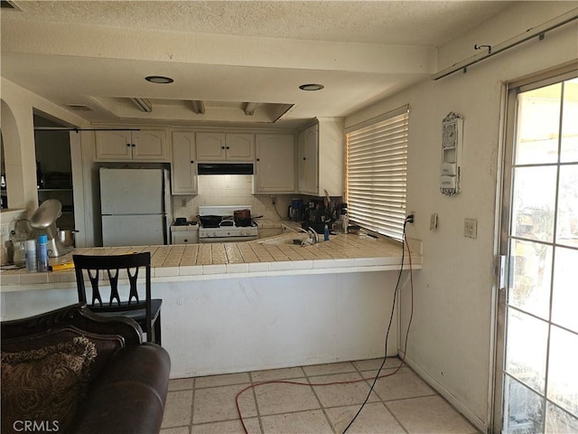 kitchen featuring decorative backsplash, white appliances, tile countertops, and light tile patterned flooring