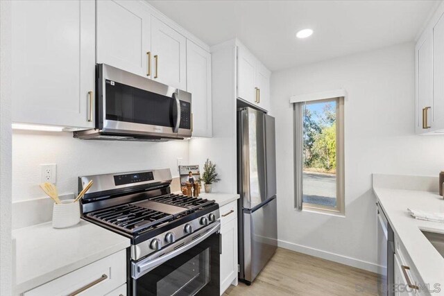 kitchen featuring stainless steel appliances, light hardwood / wood-style floors, and white cabinets