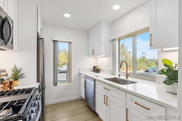 kitchen with a healthy amount of sunlight, sink, stainless steel appliances, and white cabinetry