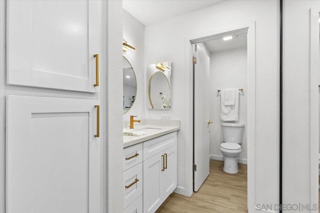 bathroom featuring toilet, hardwood / wood-style floors, and vanity