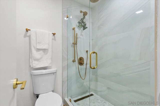 bathroom featuring toilet and a shower with door