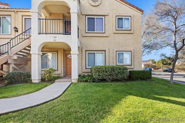 view of front of house with a front yard and a balcony