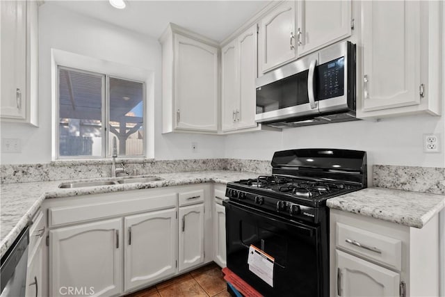 kitchen with light stone countertops, sink, white cabinetry, and stainless steel appliances