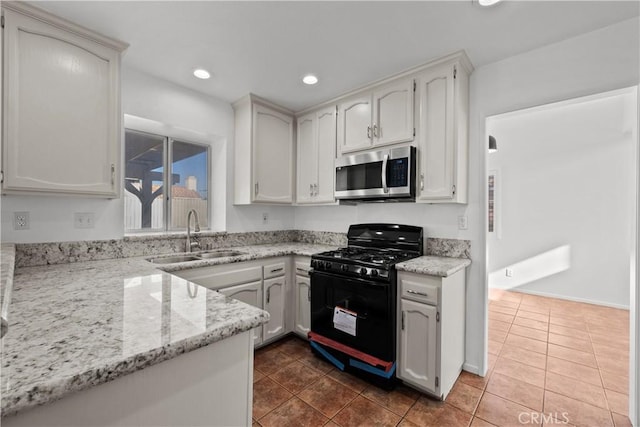 kitchen featuring dark tile patterned floors, white cabinets, sink, and black gas range