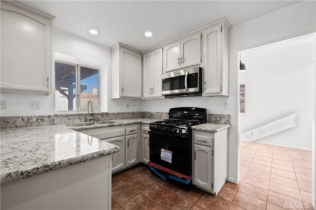 kitchen with sink, black gas stove, and white cabinetry