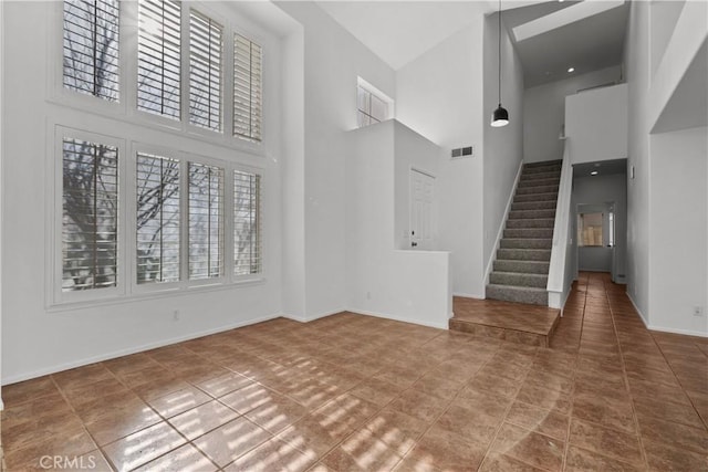 unfurnished living room featuring a towering ceiling and tile patterned flooring