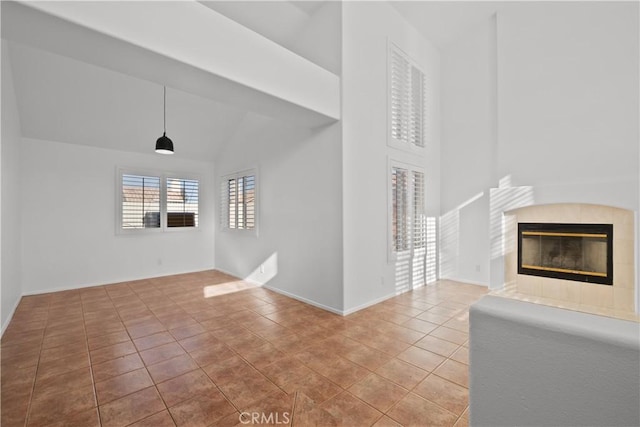 unfurnished living room with tile patterned floors, lofted ceiling, and a tiled fireplace