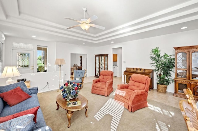 living room with ceiling fan, light tile patterned flooring, a raised ceiling, and washer / clothes dryer