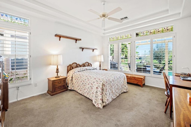 carpeted bedroom featuring ceiling fan and a tray ceiling