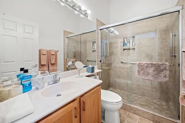 bathroom featuring toilet, vanity, and a shower with door