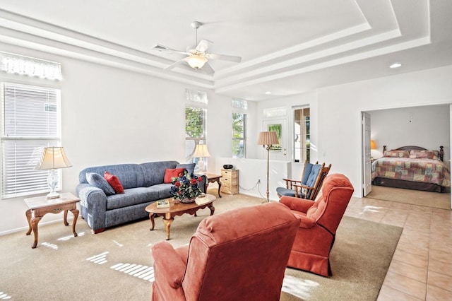 tiled living room featuring ceiling fan and a tray ceiling